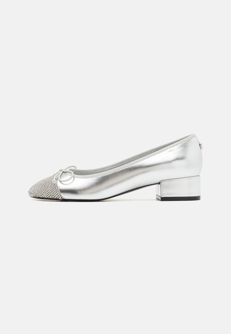 Chaussure femme argentée à talon bas avec un bout orné de strass scintillants et un petit nœud sur un fond blanc uni.