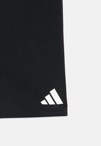 Must kangas, millel on valgel taustal alumises nurgas kolm kaldu triipu kujutav valge Adidas logo.