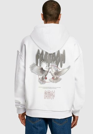 White hoodie featuring a graphic print of two doves and the word "FREEDOM" in gray. Fabric appears soft with a relaxed fit.