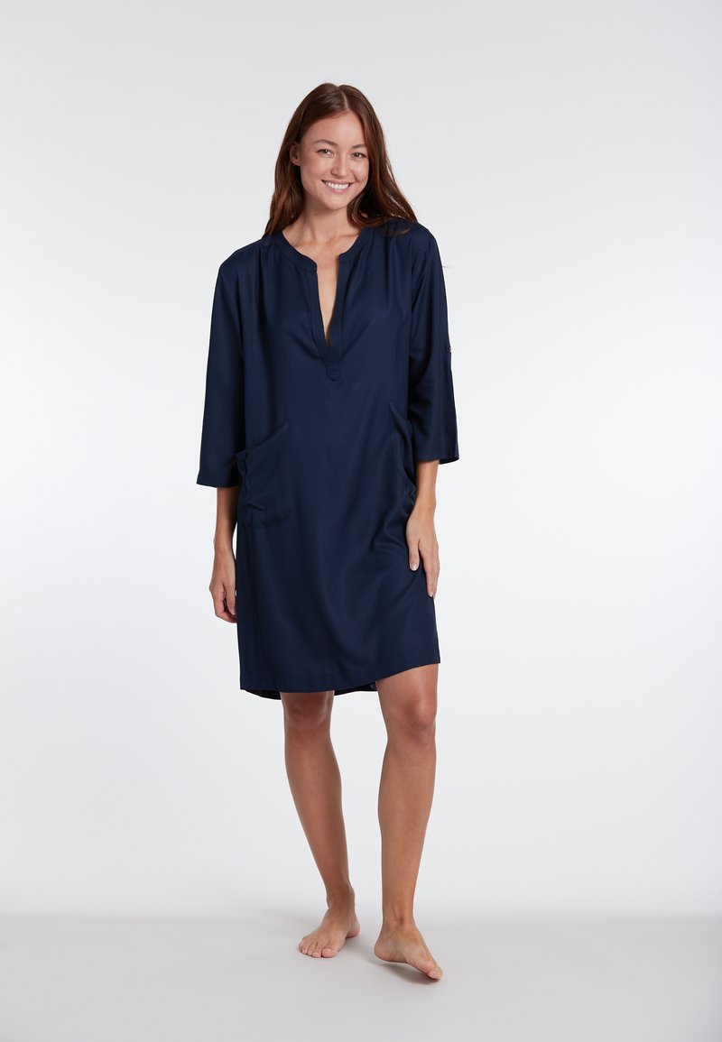 Abito blu navy con scollatura a V, maniche a 3/4 e due tasche frontali. Realizzato in tessuto morbido, ha una vestibilità comoda e una lunghezza fino al ginocchio.