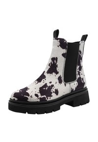 Bottines Chelsea avec un design en imprimé vache noir et blanc, dessus en fourrure texturée, panneaux latéraux élastiques et semelle épaisse en caoutchouc noir.