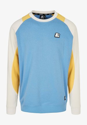 Hele sinine dressipluus valgete ja kollaste raglansleeve'idega, soonikkoes varrukad ja väike must logo rinna peal. Pehme kangast tekstuur.