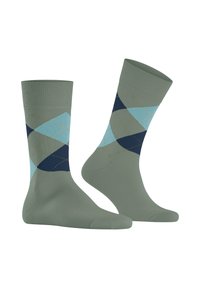 Zielone skarpetki z niebieskim, granatowym i jasnoniebieskim wzorem argyle oraz żółtymi liniami przeszycia, wyeksponowane na białym tle.