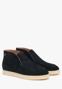Zwarte suède enkelschoenen met een gladde afwerking, witte rubberen zool en een gestikt ontwerp langs de randen. Beschikt over een klein logo-accent.