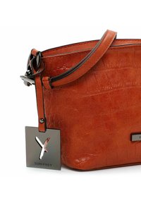 Bolso de piel naranja con un acabado texturizado similar al del cocodrilo. Presenta una etiqueta de metal negro con el nombre de la marca y una correa de hombro a juego.