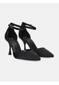 Zapatos de tacón alto de satén negro con punta afilada, correa de tobillo ajustable y tacón delgado tipo stiletto. Textura suave, diseño minimalista.