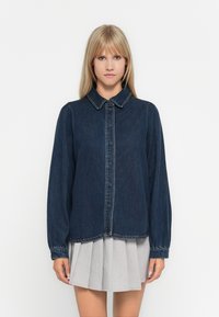 Denim shirt with a collar, dark blue fabric, buttoned front, long sleeves with gathered cuffs, and a slightly cropped hemline.