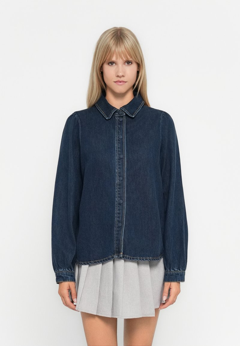 Denim shirt with a collar, dark blue fabric, buttoned front, long sleeves with gathered cuffs, and a slightly cropped hemline.