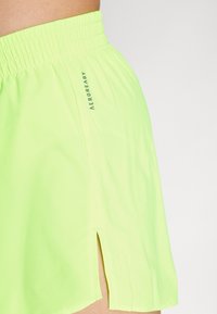 Neon groene sportshorts gemaakt van lichtgewicht materiaal, met een elastische tailleband en zij-splitten voor verbeterde bewegingsvrijheid.