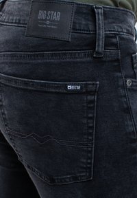 Juodi džinsai iš denim medžiagos, su odiniu Big Star etiketė, subtiliomis siuvimo detalėmis ir klasikinio penkių kišenių dizainu su sklandžiu paviršiumi.