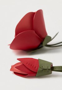 Piros bőrből készült virág zöld levél díszítéssel. Sima textúrákat, rétegzett szirmokat és dombornyomott márkanevet tartalmaz, valósághű kialakítással.