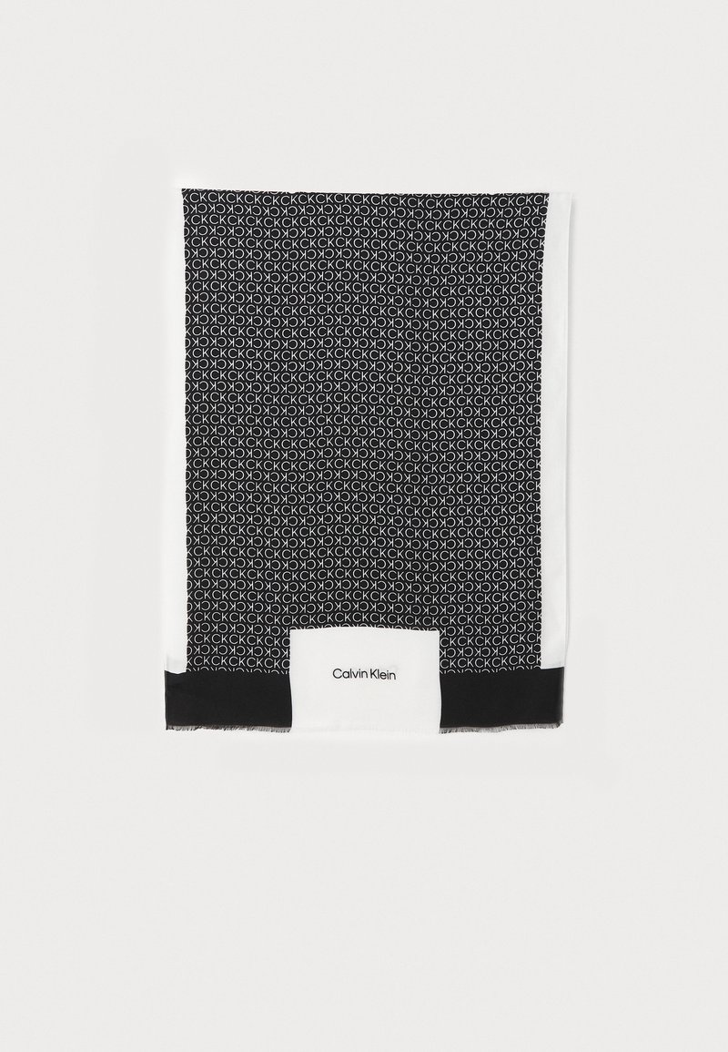 Écharpe noire et blanche avec motif répétitif "CK" et logo "Calvin Klein" sur une bande blanche près du bord.