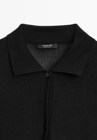 Sort strikket polo med klassisk krave, med en knaplukning og et mærke, der siger "Massimo Dutti." Blød tekstur, uformelt design.
