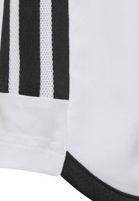 Chemise à manches courtes avec un corps principal blanc et des accents noirs, des panneaux latéraux en maille noire texturée et trois bandes noires verticales.