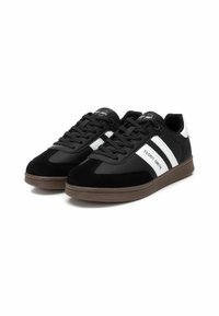 Sneaker nere con parte superiore in suede e sintetico, strisce bianche sui lati e suola in gomma marrone. Presentano lacci piatti e un collare imbottito.