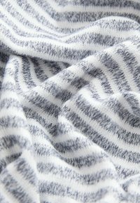 Randig stickad tyg med växlande vita och grå horisontella linjer, mjuk textur och en lätt fluffig utseende.