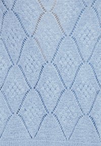 Světle modrá pletená látka s diamantovým vzorem a otevřenými detaily. Textura vypadá měkce a lehce nadýchaně, což dodává hloubku.