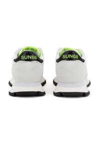 Białe sneakersy z zamszu z czarnymi akcentami i neonowo zielonym wnętrzem. Charakteryzują się zaokrąglonym kształtem, teksturowaną powierzchnią oraz ozdobnym elementem z tyłu buta z napisem "SUN68."