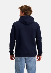 Marineblauwe hoodie met een grote capuchon, geribde manchetten en een ontspannen pasvorm. Gemaakt van zachte stof, heeft het een gestikte zoom op de taille.