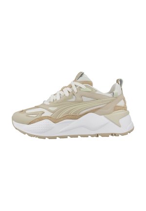 Zapatillas beige con superposiciones texturizadas, suela blanca y acentos en verde claro. Presenta cordones, collar acolchado y una silueta robusta.