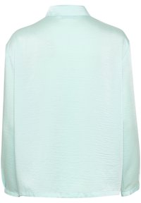Camicia azzurro chiaro a maniche lunghe con una texture liscia e lucida e un colletto morbido. Caratterizzata da una vestibilità rilassata e fessure laterali all'orlo.