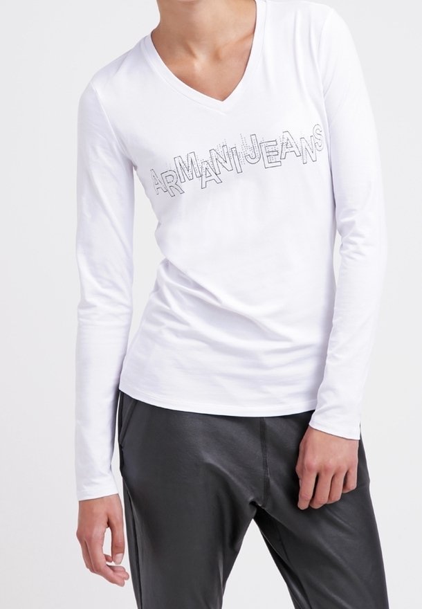 Bílé dlouhé rukávy tričko s výstřihem do V a šedým logem "ARMANIJEANS" přes přední část; hladký bavlněný materiál; upnutý střih; v kombinaci s černými kalhotami.