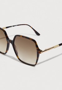 Óculos de sol de tartaruga com armação quadrada, lentes degradê castanhas, ferragens douradas e hastes finas.