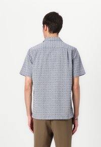 Camicia a maniche corte con colletto, di colore grigio chiaro e con un sottile motivo geometrico. Realizzata in tessuto traspirante, presenta un orlo dritto e una vestibilità rilassata.