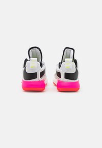Zapatillas Nike con parte superior de malla en blanco con detalles en negro y suela con degradado en rosa. Incluyen una lengüeta y un logo en contraste.