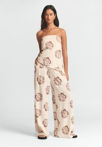 Lätt, beige strapless jumpsuit med vida ben, med ett blommönster i bruna toner. Slät textur, avslappnad design.