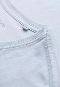 Lys blå bomuld t-shirt med rund halsudskæring, ribbede kanter og flade sømme, der fremviser en blød, glat tekstur.