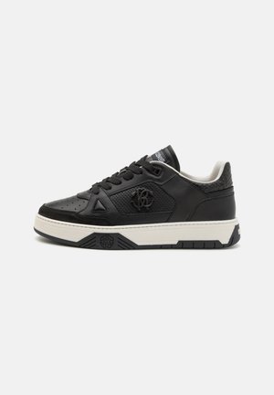 Zapatillas negras con parte superior de cuero, diseño perforado y suela de goma blanca contrastante. Presentan un logo y acentos texturizados en el talón.