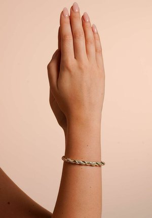 Gold-tone twisted bracelet with textured accents, displayed on a hand against a neutral background. Smooth finish, flexible design.