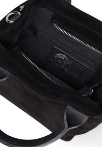 Zwarte suède schoudertas met leren accenten, een ritsvak aan de binnenkant en geët textureerde handvatten. Heeft een strakke interieur met een merklabel.