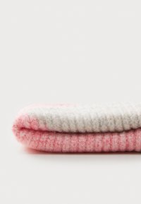 Cobertor de malha dobrado, com um degradê do rosa claro ao branco. Textura suave com uma aparência confortável, exibindo um design simples em canelado.