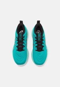Baskets de sport turquoise avec des accents noirs, dessus en mesh texturé, fermeture à lacets et semelle en caoutchouc. Comprend des logos sur la languette et sur le côté.