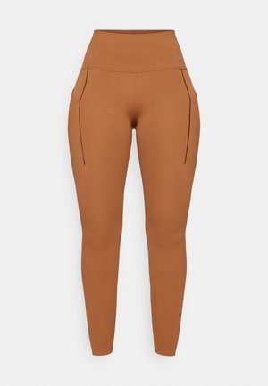 Braune hochtaillierte Leggings mit zwei Seitentaschen, aus einem glatten, elastischen Material gefertigt, mit minimalen Nahtdetails.