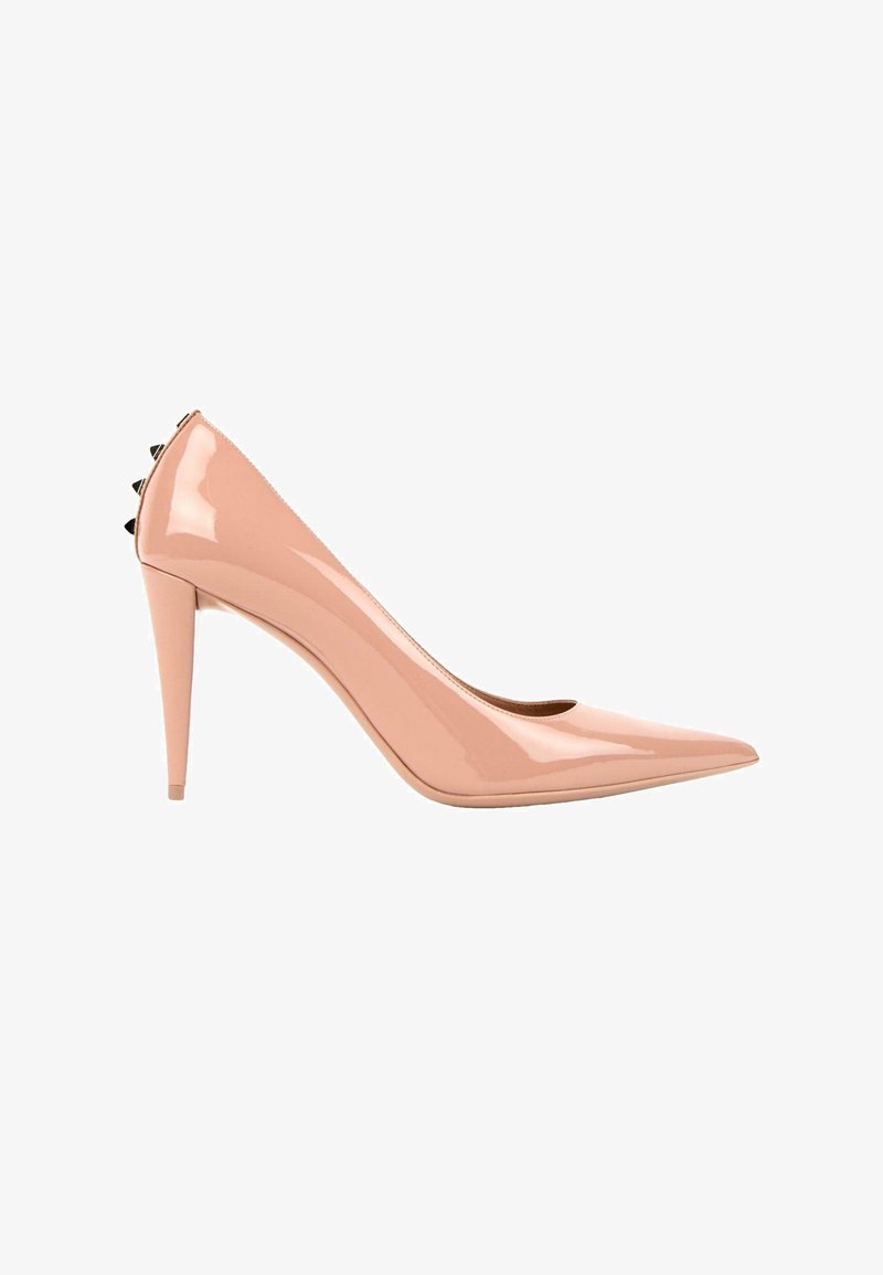 Escarpin à talon haut rose nude brillant avec bout pointu et petites pointes noires à l'arrière du talon.