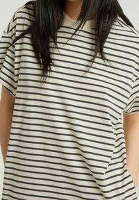 Koszulka w paski w kolorze kremowym i ciemnoszarym, o luźnym kroju, z krótkimi rękawami i okrągłym dekoltem, wykonana z miękkiego materiału.