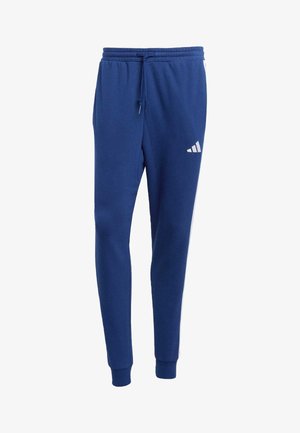 Blue tapered sweatpants with elastic waistband, drawstring, cuffed ankles, and a small white Adidas logo on the upper left thigh.