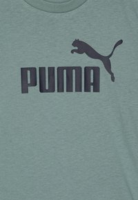 T-shirt verde menta in morbido tessuto con audace scritta nera "PUMA" e logo di un gatto che salta, scollo rotondo e maniche corte.