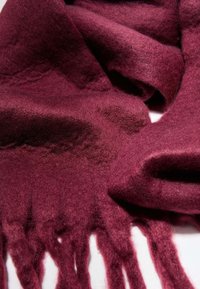 Sciarpa in lana bordeaux con una texture morbida, caratterizzata da bordi frangiati e un drappeggio leggero. Design semplice senza motivi distintivi.