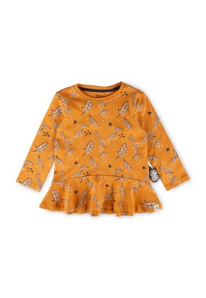 Langärmliges orangenes Oberteil mit peplum Saum, das ein Blatt- und Sternmuster in Schwarz und Weiß aufweist. Weicher Stoff mit gesteppten Akzenten.