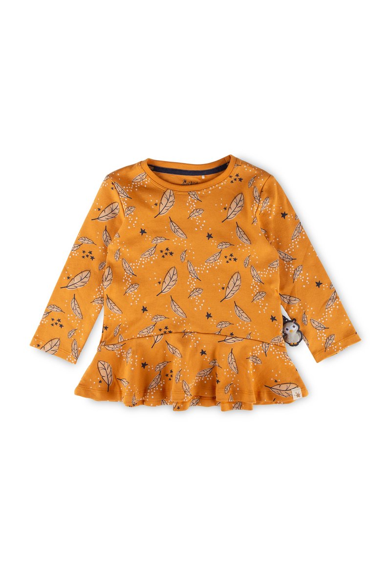 Long-sleeve orange top with a peplum hem, featuring a leaf and star pattern in black and white. Soft fabric with stitched accents.