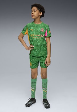 Groene voetbalkleding met een gedetailleerd patroon; bevat oranje en roze accenten. Inclusief bijpassende shorts en sokken met logo en kleurdetails.