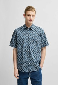 Korte mouwen overhemd met knoopsluiting in het blauw met een geometrisch patroon, voorzien van een gespreide kraag en een relaxte pasvorm. Gemaakt van lichte stof.