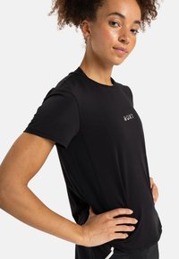 Camiseta negra de manga corta hecha de tejido suave. Presenta un cuello redondo y un pequeño logotipo en el frente "ROXY" en gris. Diseño suave y ajustado.