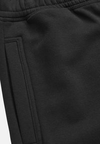 Svarta sweatpants med en slät textur, elastisk midja och en sidficka med en sydd finish. Enkelt, funktionellt design.