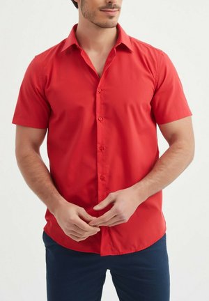Chemise rouge à manches courtes avec boutons, fabriquée en tissu lisse, caractérisée par un col classique, des boutons à l'avant et une coupe ajustée.
