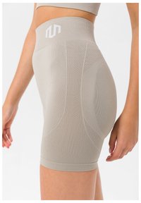 Beige høy midje sportsshorts med teksturerte paneler og logo på linningen. Laget av et elastisk materiale, ideelt for trening.